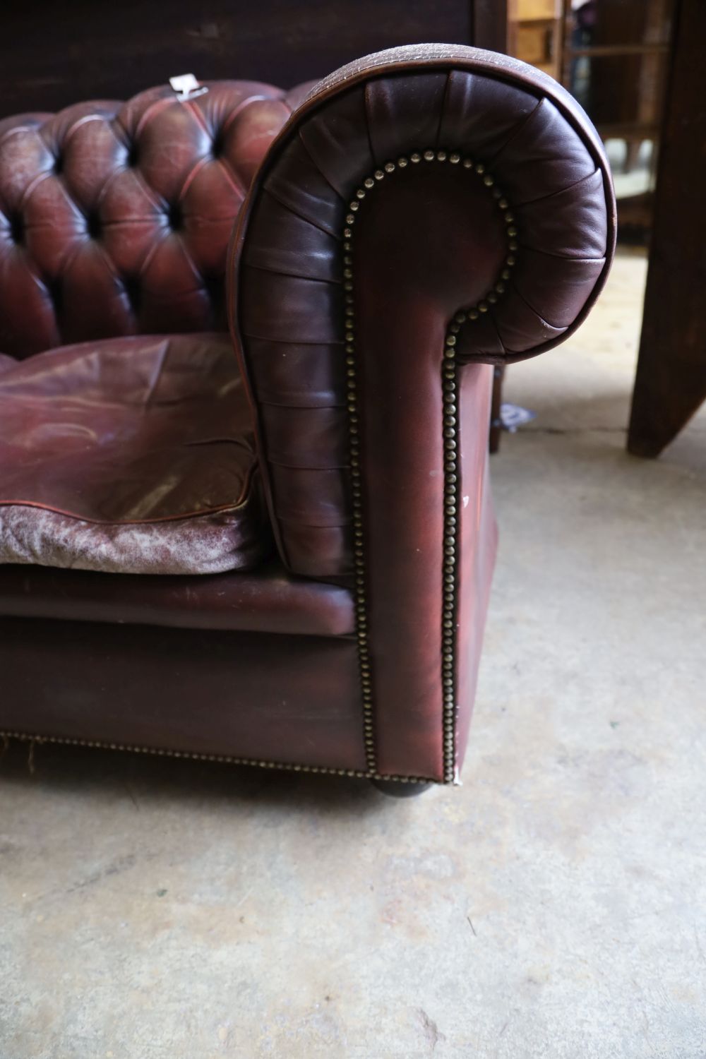 A three seater Chesterfield settee covered in deep-buttoned burgundy hide, length 210cm, depth 90cm, height 76cm